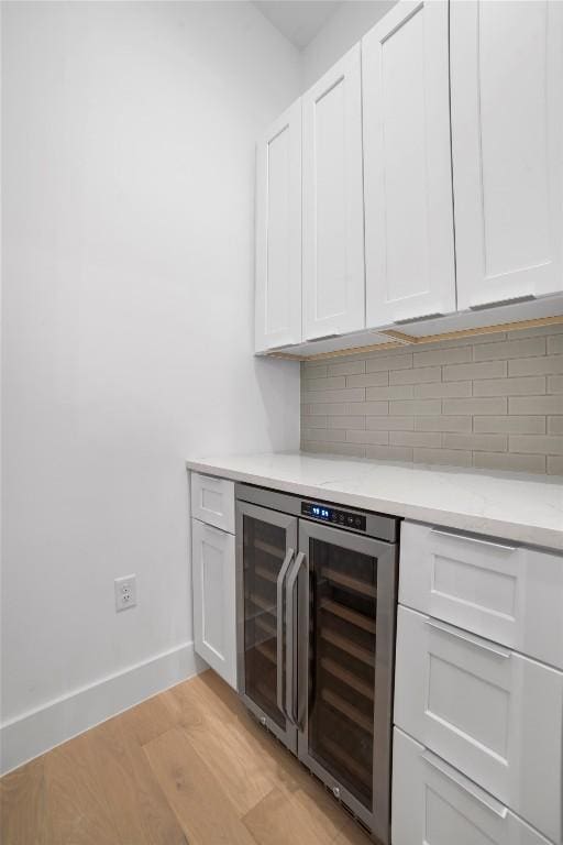 bar with white cabinetry, beverage cooler, and light wood-type flooring