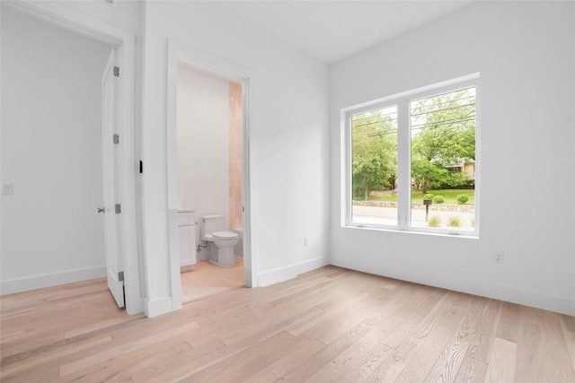 unfurnished bedroom featuring ensuite bath and light hardwood / wood-style flooring