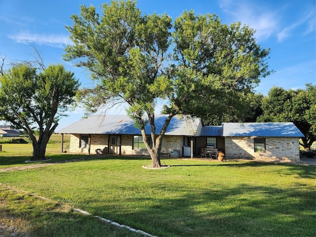 ranch-style home featuring a front yard, stone siding, and metal roof