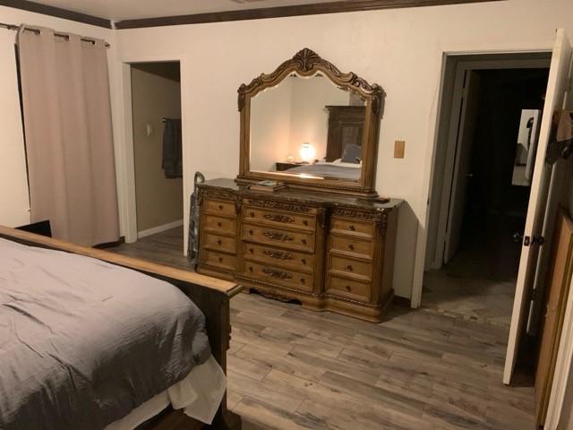 bedroom with baseboards, ornamental molding, and wood finished floors