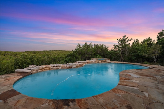 pool at dusk featuring a patio