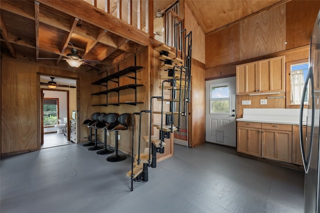 interior space featuring a healthy amount of sunlight, stainless steel refrigerator, ceiling fan, and wooden walls