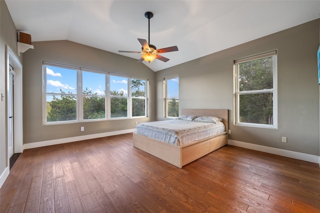 unfurnished bedroom with multiple windows, vaulted ceiling, dark wood-type flooring, and ceiling fan