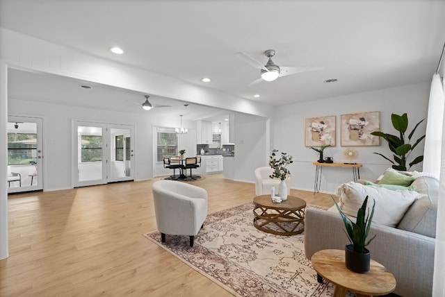 living room with recessed lighting, visible vents, ceiling fan with notable chandelier, and light wood finished floors