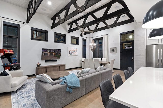 living room featuring beamed ceiling, high vaulted ceiling, light hardwood / wood-style flooring, a chandelier, and wood ceiling