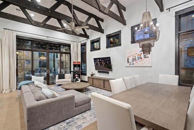 living room featuring high vaulted ceiling, ceiling fan with notable chandelier, beamed ceiling, and light hardwood / wood-style flooring