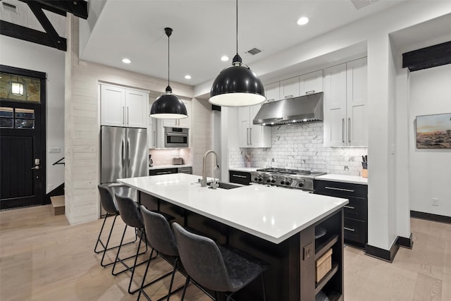 kitchen featuring a kitchen island with sink, light wood-type flooring, white cabinetry, and stainless steel appliances