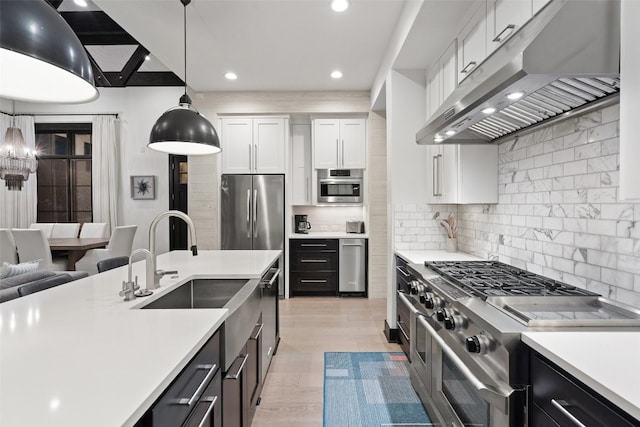 kitchen featuring appliances with stainless steel finishes, tasteful backsplash, hanging light fixtures, white cabinetry, and light wood-type flooring