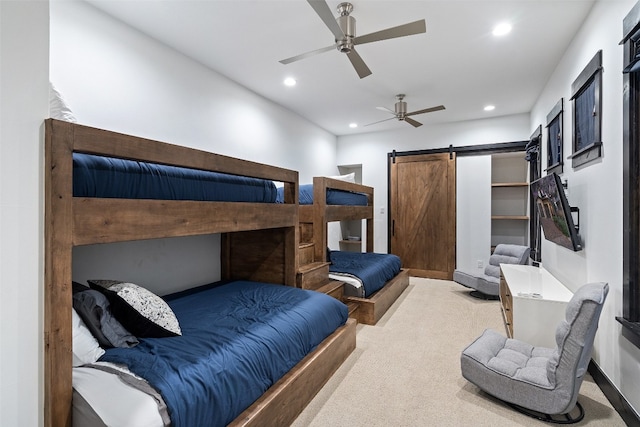 bedroom featuring a barn door, ceiling fan, and light carpet