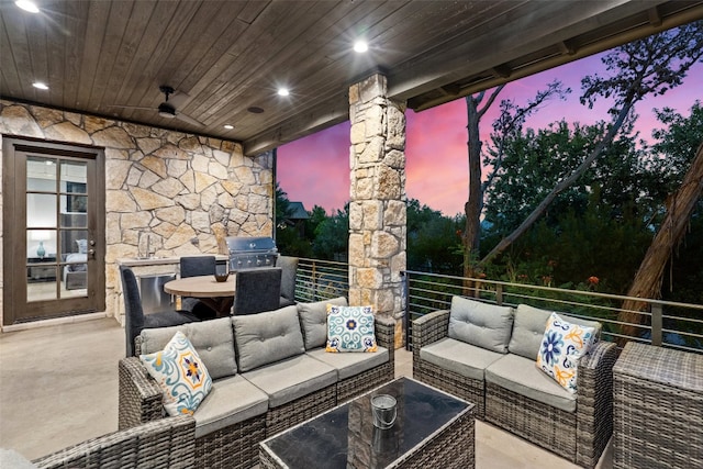 patio terrace at dusk with an outdoor living space, exterior kitchen, and area for grilling