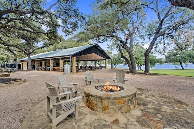 view of community with a water view, a patio area, and a fire pit