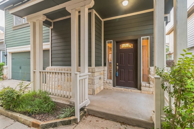 view of exterior entry with a garage and covered porch