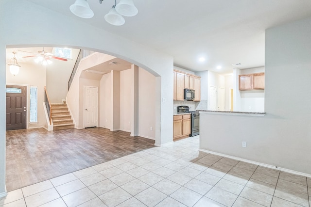 interior space with black appliances, ceiling fan, light hardwood / wood-style flooring, and light brown cabinetry