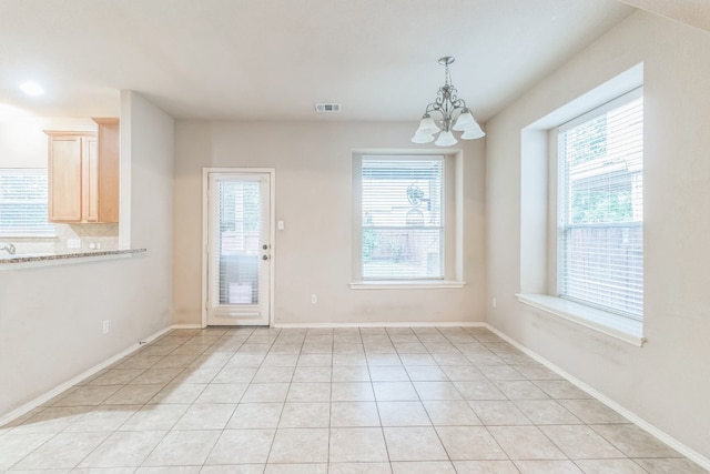 unfurnished dining area with an inviting chandelier and light tile patterned flooring