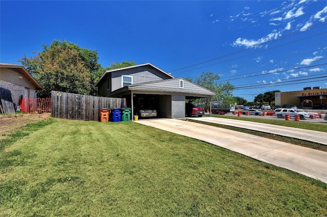 exterior space with concrete driveway, fence, and a front yard
