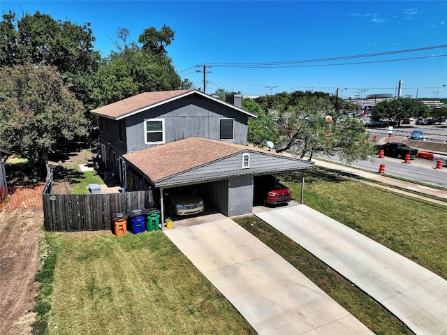 view of front facade featuring fence, driveway, an attached carport, and a front yard
