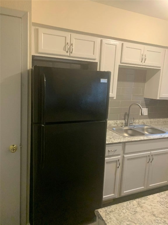 kitchen featuring light countertops, a sink, freestanding refrigerator, tasteful backsplash, and white cabinetry