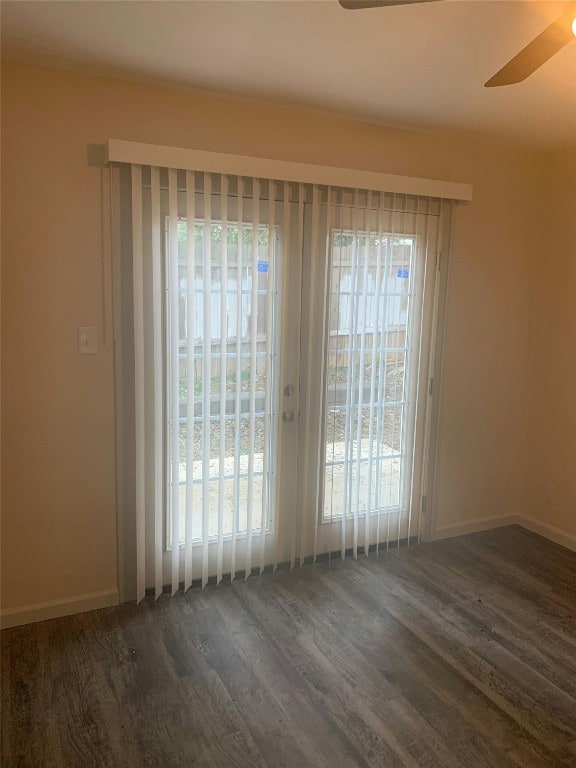 empty room featuring baseboards, a ceiling fan, and dark wood-style floors