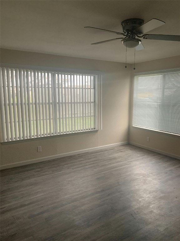 spare room with baseboards, wood finished floors, and a healthy amount of sunlight