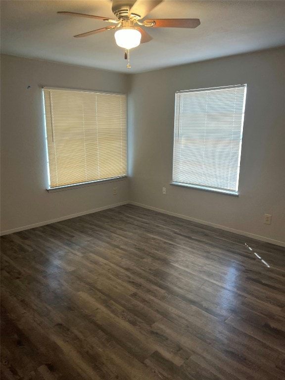 empty room with baseboards, dark wood-style floors, and ceiling fan