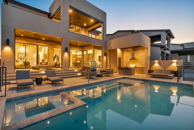 pool at dusk featuring exterior kitchen, an outdoor hangout area, and a patio area