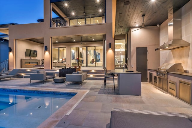 view of pool with area for grilling, ceiling fan, a patio area, and an outdoor kitchen