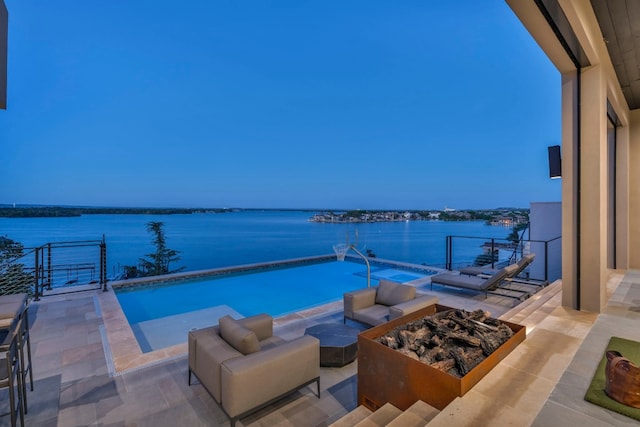 view of pool with an outdoor living space with a fire pit, a patio, and a water view