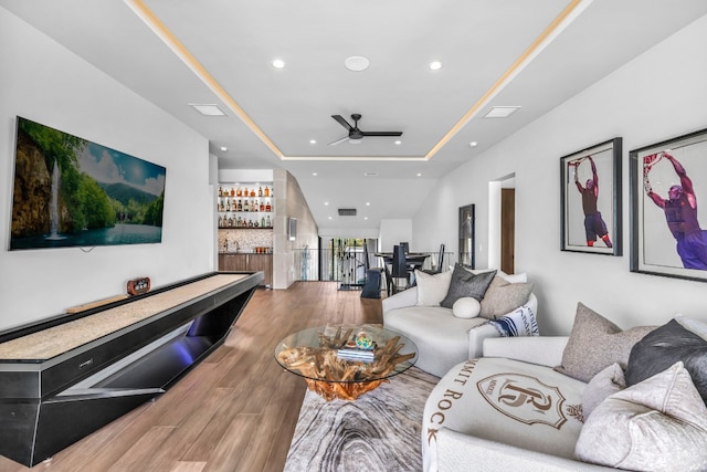 living room featuring a tray ceiling, wood-type flooring, and ceiling fan