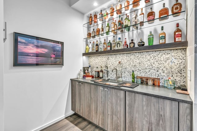 bar featuring dark hardwood / wood-style floors, tasteful backsplash, and sink