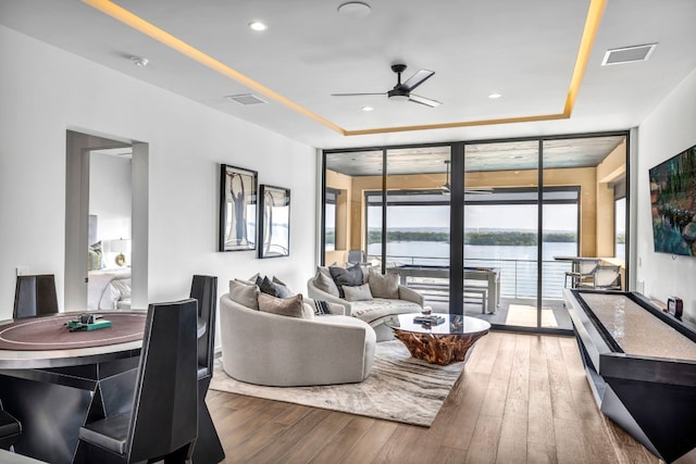 living room with expansive windows, a tray ceiling, ceiling fan, and dark hardwood / wood-style floors