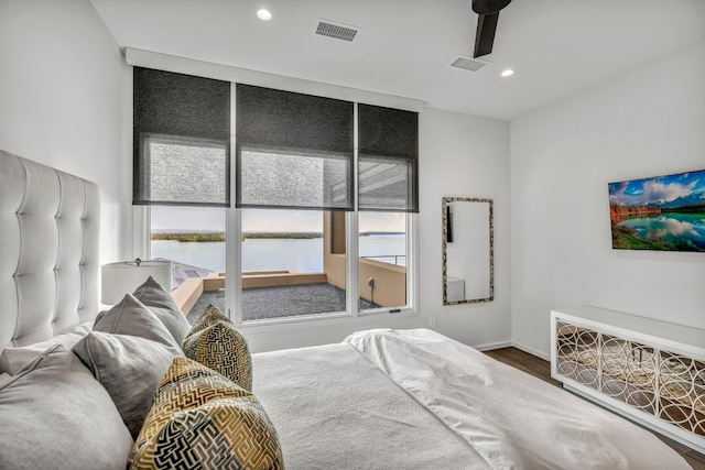 bedroom featuring a water view, wood-type flooring, and ceiling fan