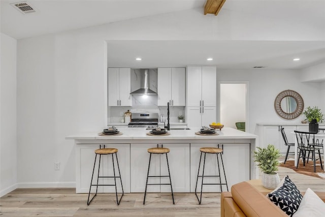 2110 Malvern Hill Dr, Austin, TX 78745 - kitchen featuring wall chimney range hood, stainless steel range oven, a kitchen bar, white cabinetry, and recessed lighting