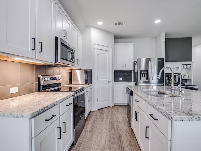 kitchen featuring a center island with sink, light hardwood / wood-style flooring, appliances with stainless steel finishes, sink, and white cabinetry