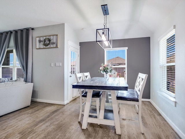 dining space featuring vaulted ceiling, plenty of natural light, and light hardwood / wood-style flooring