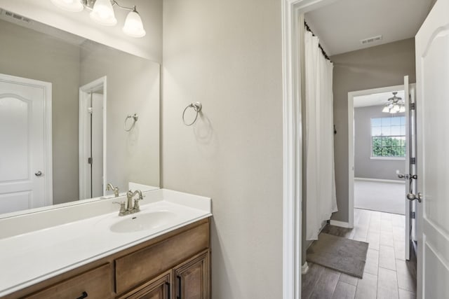 bathroom with hardwood / wood-style floors, ceiling fan, and vanity