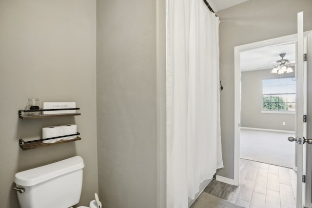 bathroom featuring toilet, hardwood / wood-style flooring, and ceiling fan