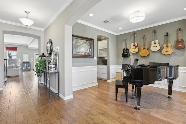 2717 Highland Trl, Leander, TX 78641 - living area featuring arched walkways, wood finished floors, a wainscoted wall, ornamental molding, and recessed lighting