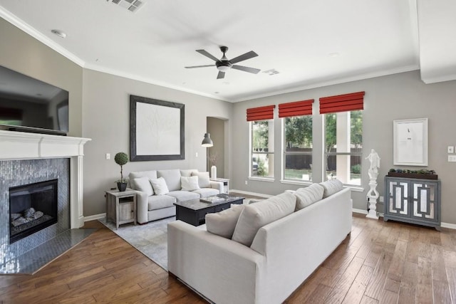 2717 Highland Trl, Leander, TX 78641 - living area with wood-type flooring, ceiling fan, a fireplace, crown molding, and baseboards