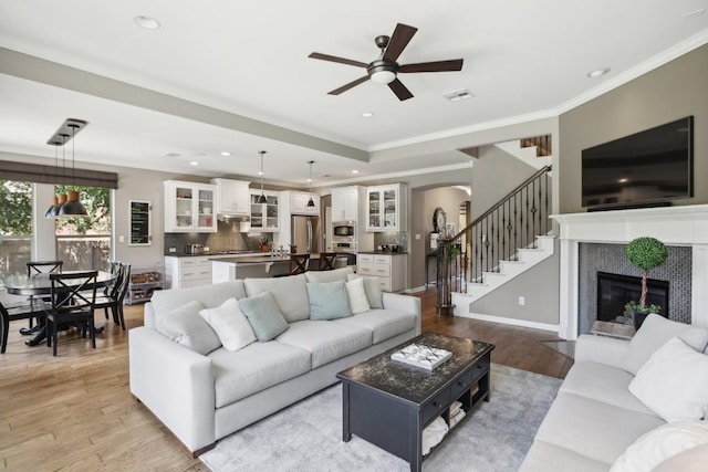2717 Highland Trl, Leander, TX 78641 - living room featuring a ceiling fan, light wood-style floors, arched walkways, a fireplace, and recessed lighting