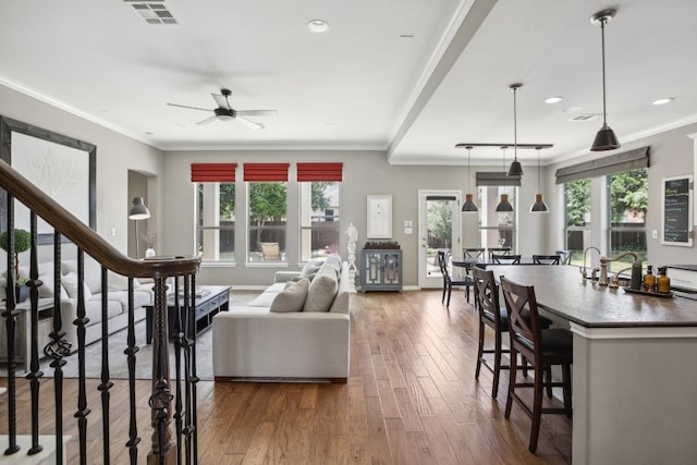 living room with dark wood-type flooring, ceiling fan, and ornamental molding