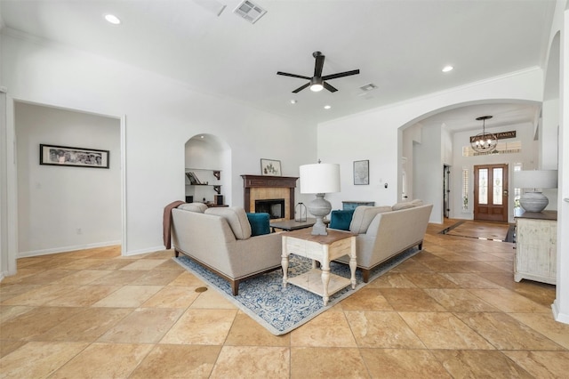 living room featuring a fireplace, ceiling fan with notable chandelier, and ornamental molding