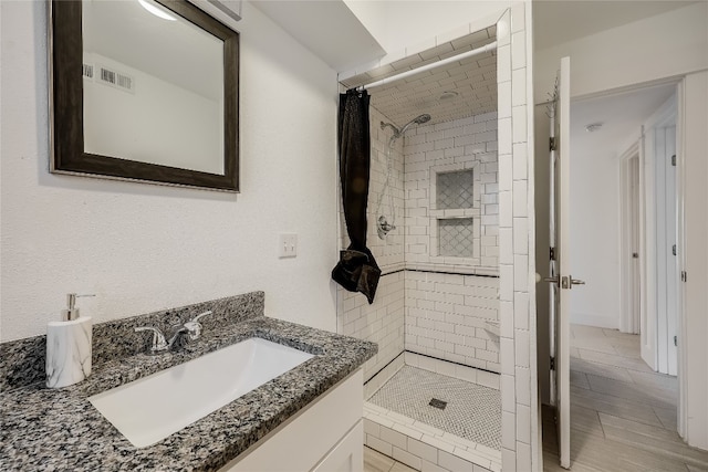 bathroom with a tile shower and vanity