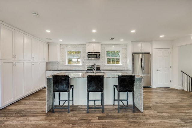 kitchen featuring a breakfast bar area, a kitchen island with sink, stainless steel appliances, and white cabinets