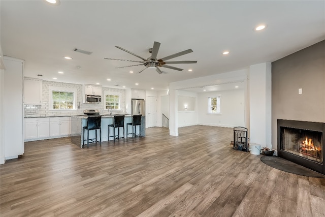 living room with light hardwood / wood-style floors, sink, and ceiling fan