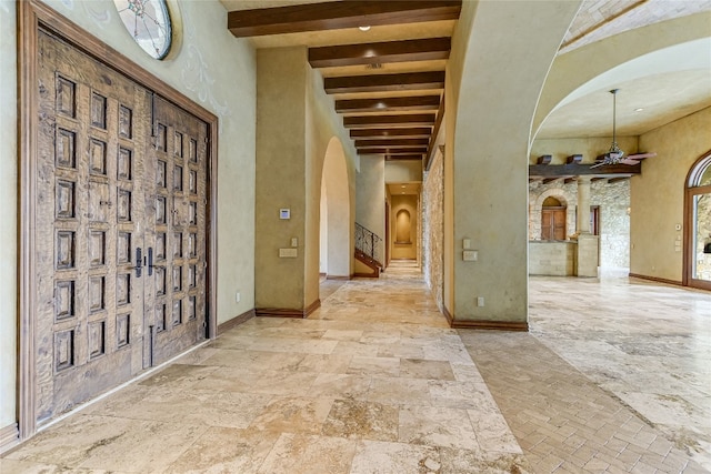 entryway with beamed ceiling and a high ceiling