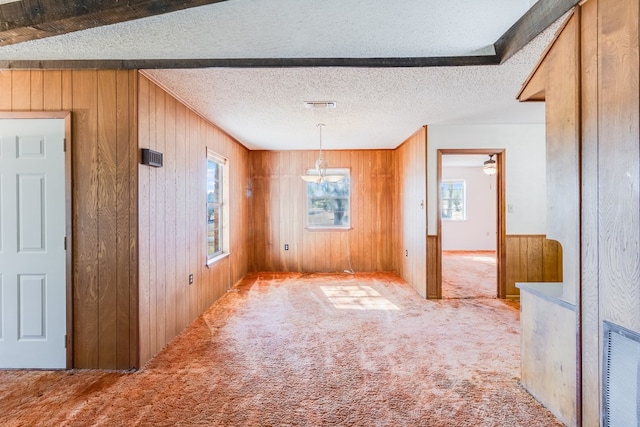 carpeted spare room featuring a textured ceiling and wooden walls