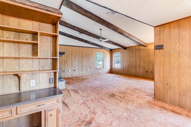 interior space featuring a textured ceiling, beamed ceiling, wood walls, and ceiling fan