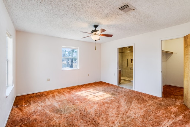 unfurnished bedroom with ensuite bath, ceiling fan, a walk in closet, and carpet floors