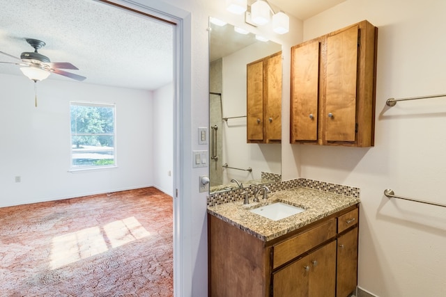 bathroom with ceiling fan, vanity, and a textured ceiling