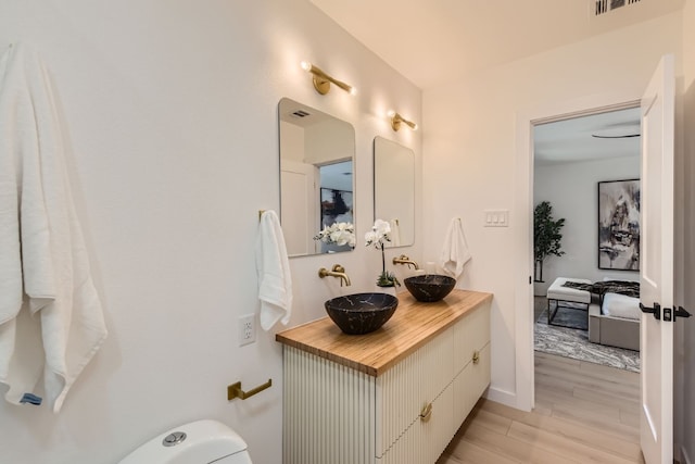 bathroom featuring wood-type flooring, toilet, and vanity